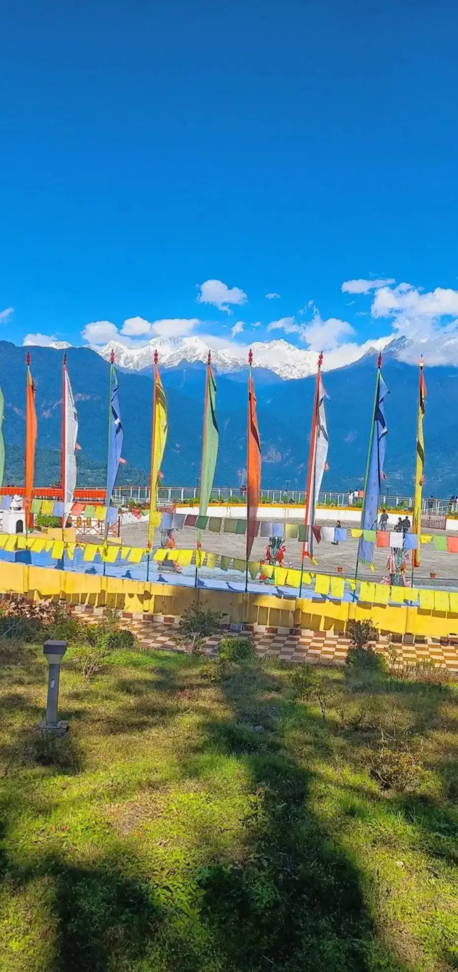 Colorful Buddhist prayer flags, known locally as Dhajas, with snow-capped Himalayan mountains in the background at Sky Walk, Pelling, Sikkim.