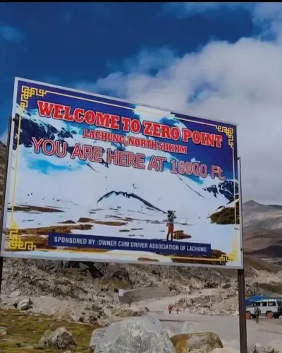 Zero point banner in the valley, the banner write welcome to zero point lachung north sikkim. the sky is blue and has white coluds with beautiful valley scene